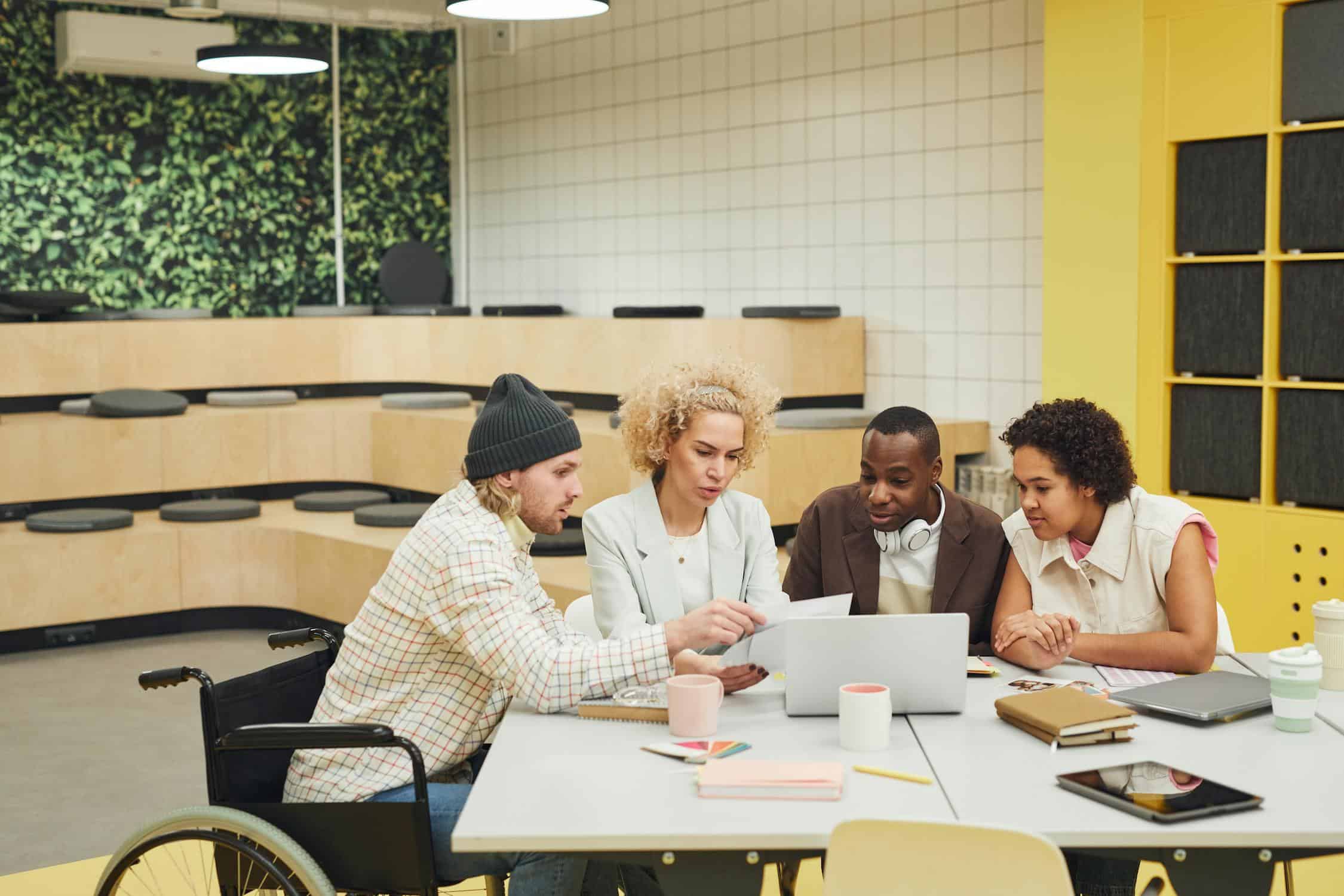 Leadership team discussing strategies around a laptop in a bright, modern office setting.