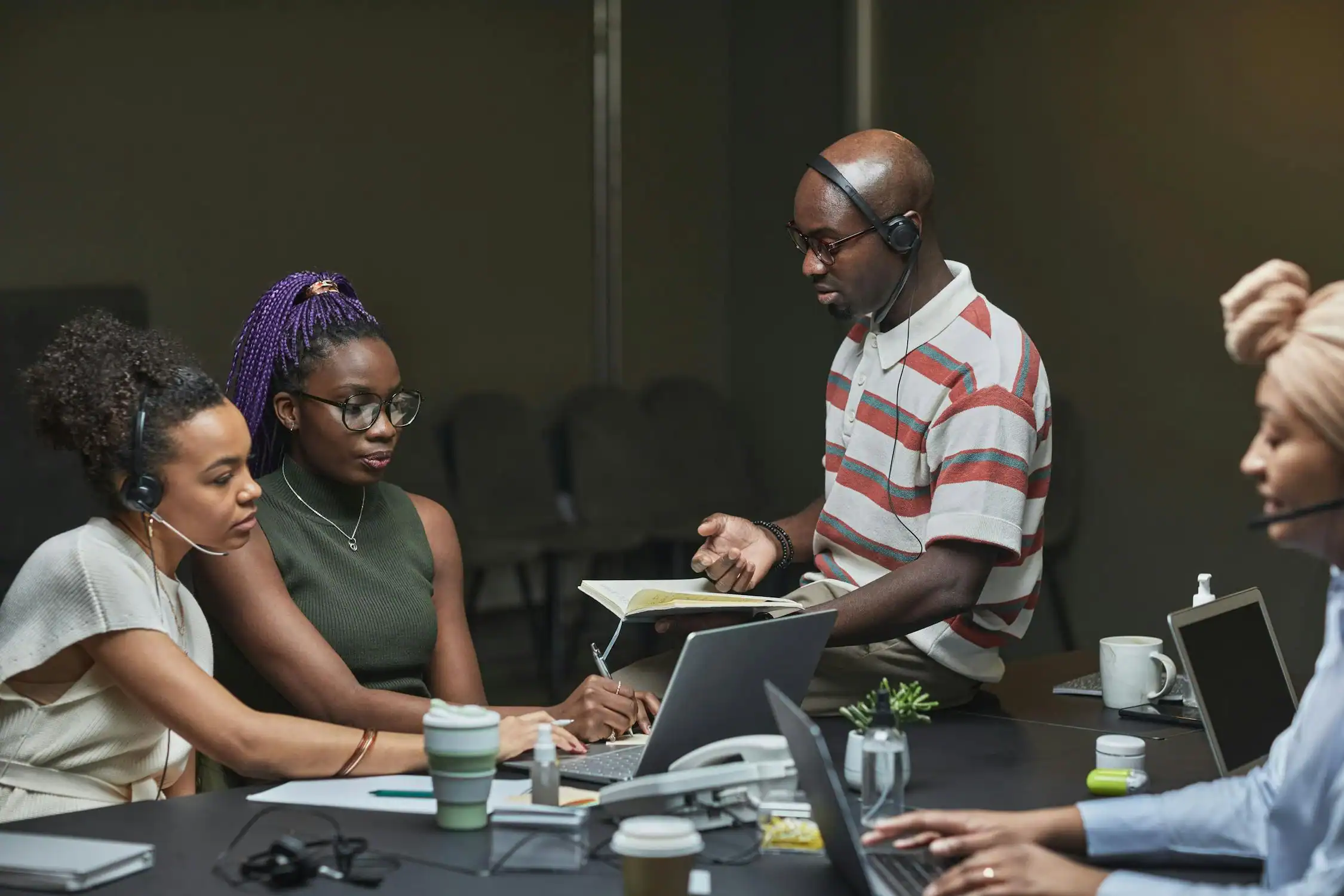 Leadership team collaborating during a business meeting with headsets and laptops.