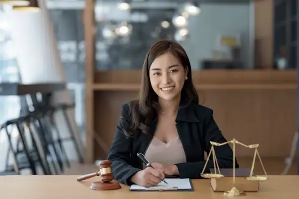 Lawyers and Law Firms Marketing 1 Young female lawyer working at desk with legal scales and gavel.