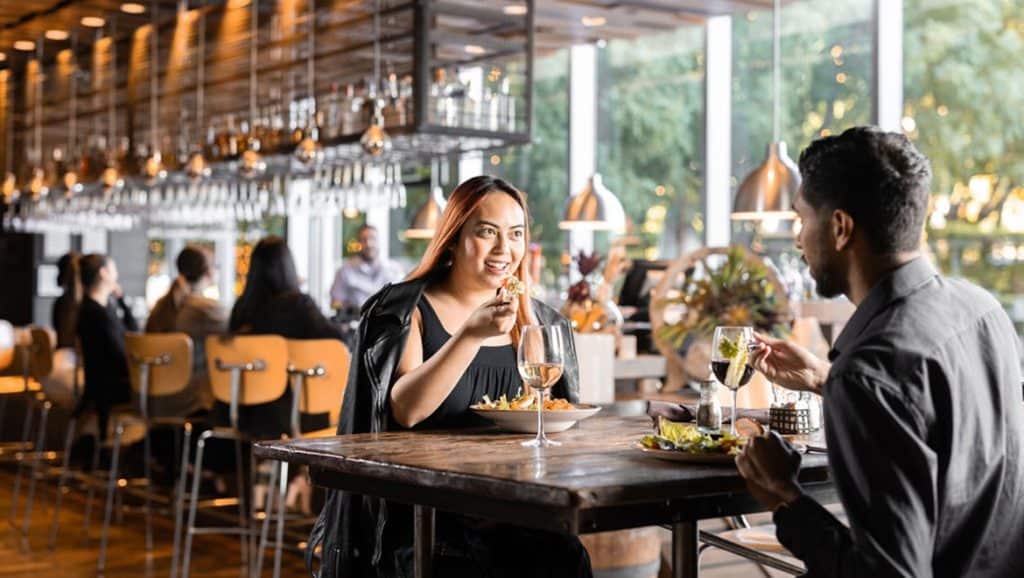 Modern restaurant scene with customers enjoying meals and drinks indoors.